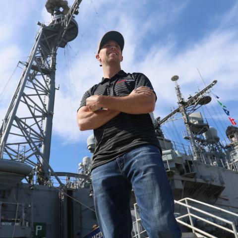 Coca-Cola Racing Family driver Denny Hamlin stands near the USS San Jacinto at Naval Station Norfolk in Norfolk, Virginia, on Thursday, April 11, 2019, as part of Charlotte Motor Speedway’s Mission 600 campaign.