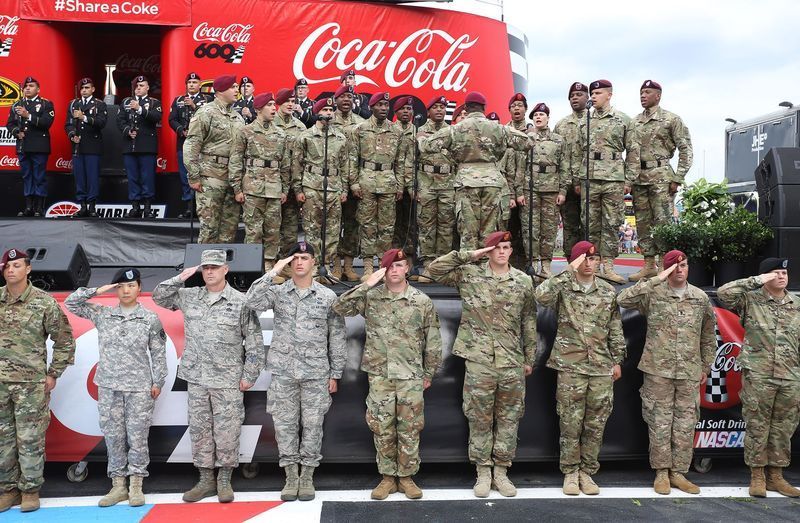 Military members stand and salute during pre-race festivities at the Coca-Cola 600 at Charlotte Motor Speedway.