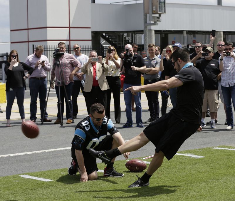 Carolina Panthers kicker Graham Gano boots a field goal on Charlotte Motor Speedway's pit road to open the Motorsports Month of May, as NASCAR driver Austin Dillon holds. 
