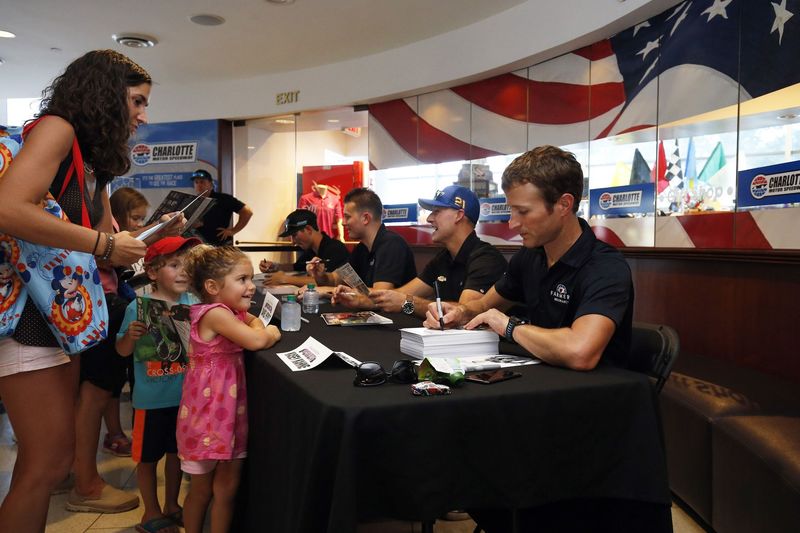 NASCAR driver Kasey Kahne, right, signs an autograph for a young fan during Charlotte Motor Speedway's Parade of Power event on Wednesday.