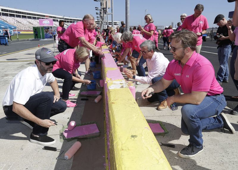 NASCAR driver Jimmie Johnson, left, joined Blue Cross and Blue Shield of North Carolina dignitaries and breast cancer survivors as well as Marcus Smith, Speedway Motorsports, Inc. chief executive officer, right, in painting the speedway's pit wall pink on Wednesday.