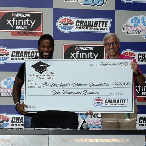 DeAngelo Williams, left, receives a $10,000 check for the DeAngelo Williams Foudnation from Charlotte Motor Speedway Executive Vice President Greg Walter on Saturday at Charlotte Motor Speedway.