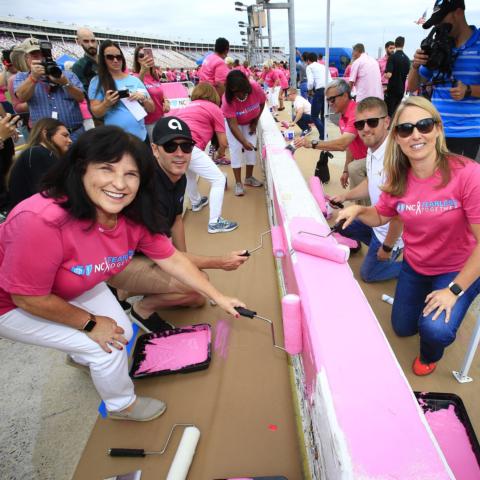Seven-time NASCAR Cup Series champion Jimmie Johnson, second from left, joined NASCAR drivers including Justin Allgaier, second from right, and Blue Cross and Blue Shield of North Carolina dignitaries Robin Miller, front left, and Reagan Greene Pruitt, front right, in painting Charlotte Motor Speedway's pit road wall pink on Wednesday in honor of breast cancer awareness.