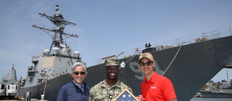 Coca-Cola Racing Family driver Joey Logano (right), Charlotte Motor Speedway Executive Vice President and General Manager Greg Walter (left) and NASCAR Salutes ambassador Jesse Iwuji pose for the photo in front of the USS Nitze during a Mission 600 visit to Naval Station Norfolk on Wednesday, May 10.