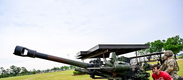 Coca-Cola Racing Family driver Daniel Suarez prepares to fire an M119A3 Howitzer 105mm blank during a visit with the 82nd Airborne Division at Fort Liberty as part of Charlotte Motor Speedway's Mission 600 campaign. The event pairs drivers with regional military bases to learn and train alongside service men and women as a prelude to the Coca-Cola 600 on Memorial Day Weekend.