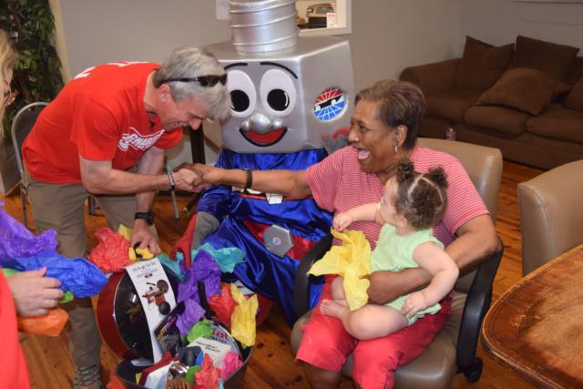 Charlotte Motor Speedway Executive Vice President Greg Walter, left, joined speedway mascot Lug Nut in presenting Opportunity House cook Addie Payne with a special gift basket  of new utensils during the speedway's Service Day on Wednesday.