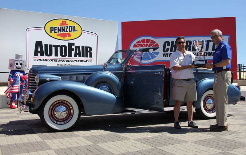 Brian De Pouli, left, holds the Best of Show trophy alongside Charlotte Motor Speedway Executive Vice President Greg Walter on Sunday during the Pennzoil AutoFair presented by Advance Auto Parts.