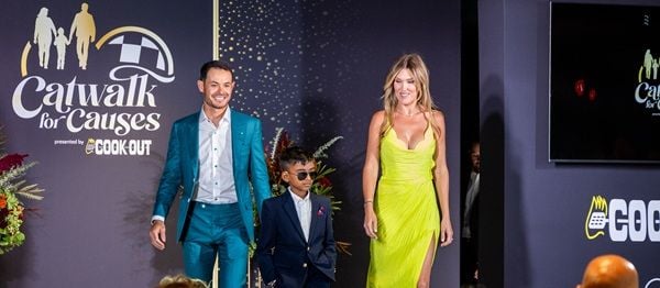 Kyle and Katelyn Larson, representing the Kyle Larson Foundation, walk the runway with seven-year-old Jeffrey during Tuesday's Catwalk for Causes at Ten Tenths Motor Club.