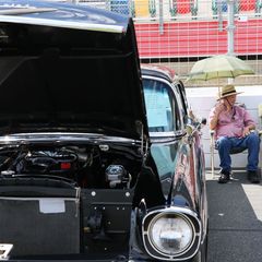 A car enthusiast seeks shade during a beautifully sunny opening day of the Pennzoil AutoFair presented by Advance Auto Parts.
