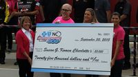 Blue Cross Blue Shield of North Carolina brand ambassador Mia Hamm and senior vice president and chief human resources officer Fara Palumbo present a check to the Susan G. Komen Foundation to kick off Breast Cancer Awareness Month and preview the Drive for the Cure 300 NASCAR XFINITY Series race at Charlotte Motor Speedway.