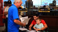 Motorsports analyst Wendy Venturini (with her son, Caleb) sign autographs during the seventh annual Parade of Power at Charlotte Motor Speedway on Wednesday.