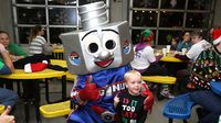 Lug Nut poses for a photo with a young fan during opening night of the sixth annual Speedway Christmas at Charlotte Motor Speedway.