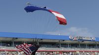 A parachuter flies into the track with an American flag during elimination Sunday at the NHRA Carolina Nationals at zMAX Dragway.