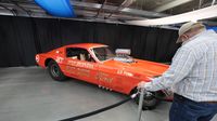 Visitors read up on some of the historic Funny Car dragsters on display during opening day at the Pennzoil AutoFair at Charlotte Motor Speedway.