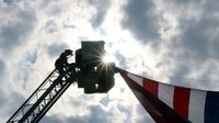 A Concord firefighter climbs a ladder truck to lower the American flag following opening ceremonies for the 6th annual Laps for Life event at Charlotte Motor Speedway.