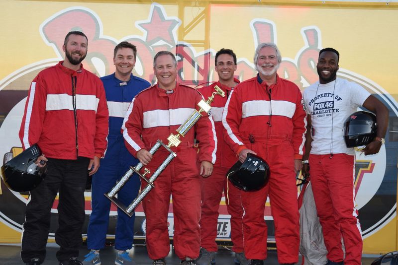 From left: Spectrum News' Matthew East, WCCB's Derek James and race winner Al Conklin from WBTV join WCNC's Nick Carboni, Cabarrus County Channel 22's David Baxter and WJZY's Josh Sims after the Media Mayhem bus race during Tuesday's Bojangles' Summer Shootout at Charlotte Motor Speedway.
